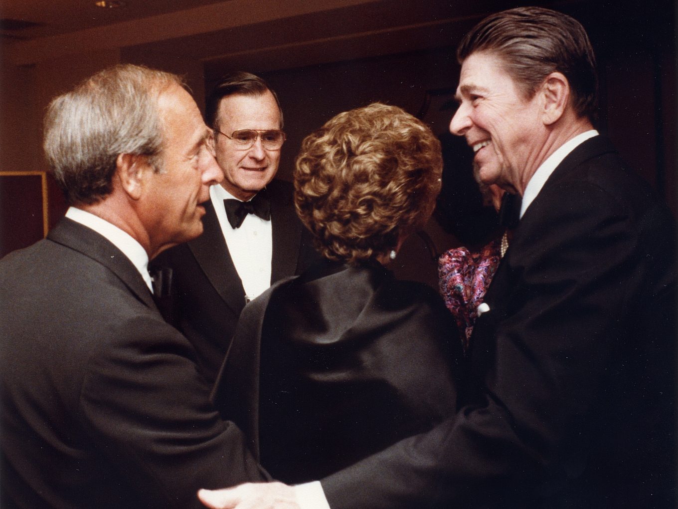 Rich DeVos greets former President Ronald Reagan at an event. Former President George H.W. Bush can be seen in the background.