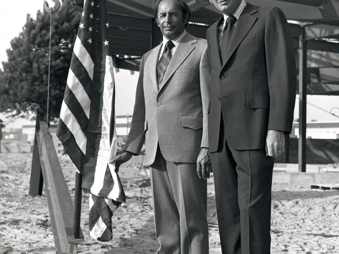 In this black and white image, Rich and Jay raise the American flag on the construction site of the Center of Free Enterprise.